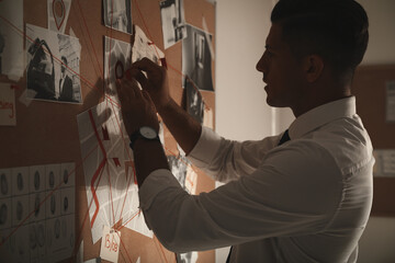 Detective looking at evidence board in office