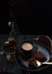 Closeup view of an elegant tray with a foamy coffee, a slice of cake and a golden spoon over it with a little piece of cake.
