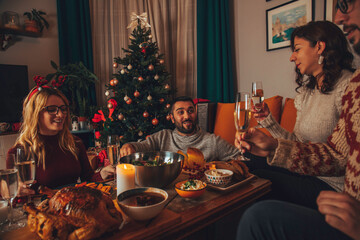 Group of friends having dinner at home on Christmas eve. Happy New Year and Merry Christmas.