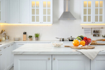 Different fresh vegetables and mushrooms on white table in modern kitchen. Space for text