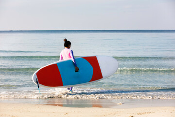 Beautiful and slim woman hold surf board to the sea, Sport girld concep