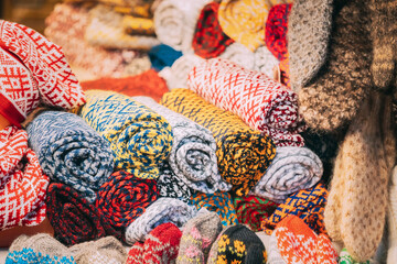 Fototapeta na wymiar Various Colorful Knitted Traditional European Warm Clothes - Scarfs At Winter Christmas Market. Winter Souvenir