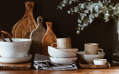 Set of kitchen ceramic tableware and wooden cutting boards on a table. Eco style home still life.