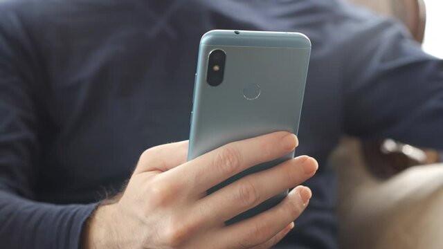 Smartphone. Young adult hand holding and using mobile phone technology device indoors front view 4K.