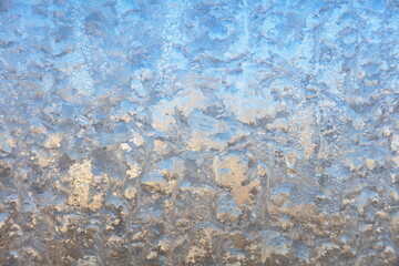 Winter background on a transparent glass of a window with a frozen texture