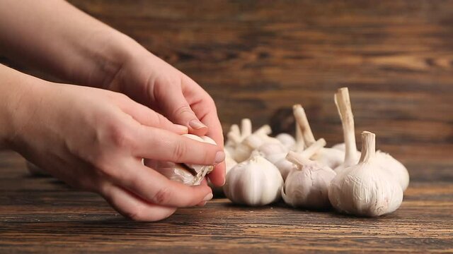 Woman breaking apart garlic on wooden table