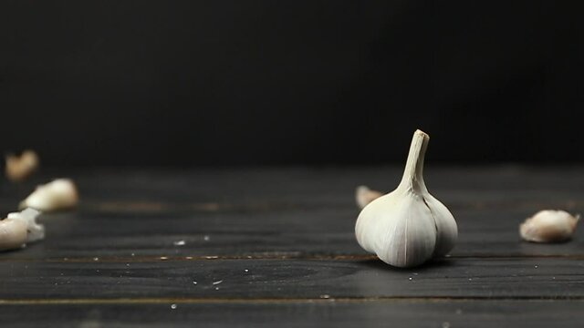 Falling garlic cloves on dark wooden table
