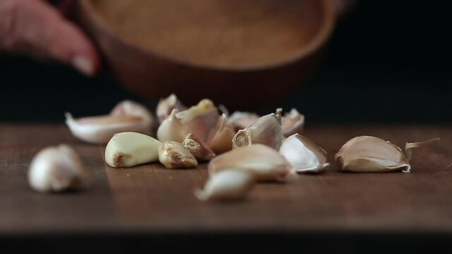 Throwing of garlic cloves from bowl on table, closeup