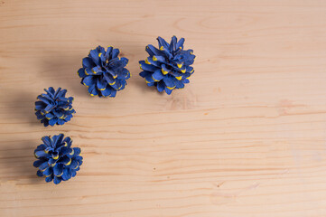 four small pine cones painted blue, isolated on wooden background