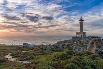 Fototapeta na wymiar sunset at the Punta Nariga lighthouse in Galicia with a gray camper van parked there