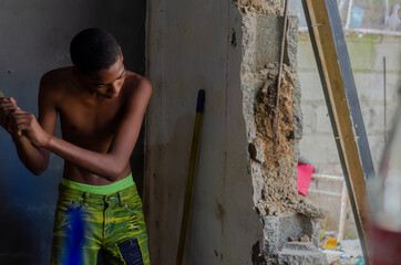 Haitian Latino boy working on construction hammering the wall to knock it down