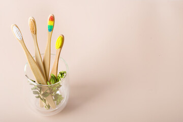 bamboo toothbrushes on a beige background in a glass glass
