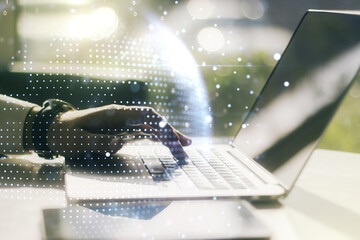 Double exposure of abstract digital world map and hand typing on laptop on background, big data and blockchain concept