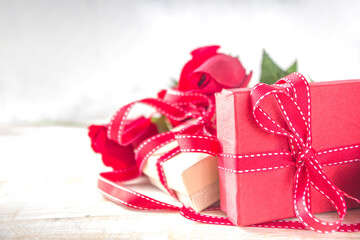 Valentines Day concept, Red Roses and Gift Boxes with Festive Ribbon and Heart Decor on White wooden table background copy space. Romantic floral background.