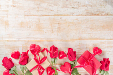Fototapeta na wymiar Valentines Day concept, Red Roses and Gift Boxes with Festive Ribbon and Heart Decor on White wooden table background copy space. Romantic floral background.