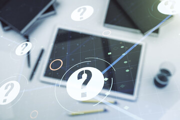 Creative abstract question mark hologram and modern digital tablet on desktop on background, top view, future technology concept. Multi exposure