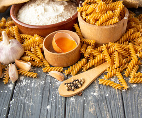 wholemeal raw pasta fusilli type, flour and egg, garlic on an old table