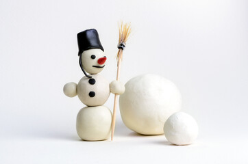 Plasticine snowman with broom and two balls on white background