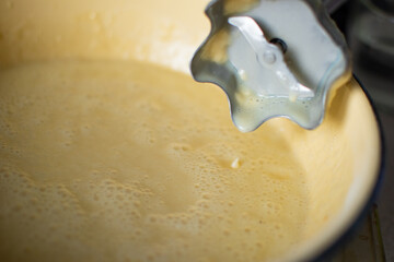 Batter or liquid dough for cooking a tasty pie in yellow metal dish (very shallow DOF) with blender