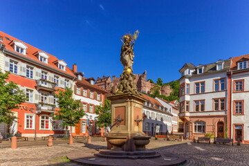 Fototapeta na wymiar The Madonna statue in Kornmarkt square and castle in Heidelberg by day, Germany
