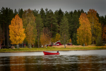 little red boat on the lake in autumn near the red houses