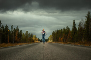 woman runs on a road in the autumn forest