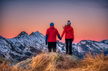 couple of people watch the sunset from a mountain