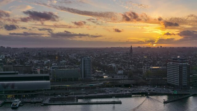4k time lapse overlooking the historic city center of Amsterdam with the central train station and river IJ during sunset with ferries and trains transporting commuters