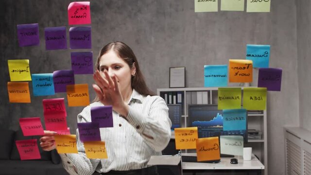 Timelapse of the young business woman is doing brainstorm using stickers on the glass. Office worker is thinking about strategy, business plan and goals. Startup concept.