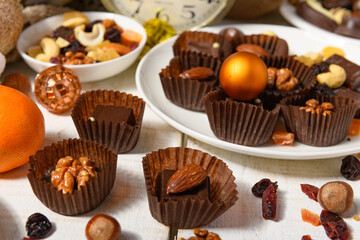 sweet food background for christmas or holiday decoration - chocolate candies, tangerines, nuts and dried fruits on white wood