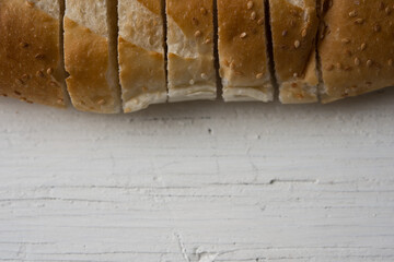 Fresh bread sliced baguette on rustic white table top view