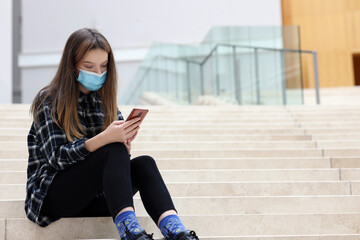 young beauty teen in medical mask using mobile phone