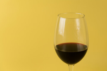 glass of red wine on a yellow background. Close-up view. Isolated yellow background
