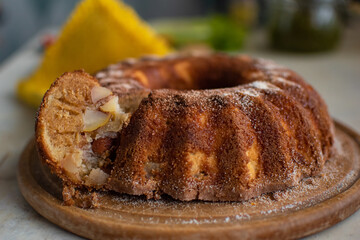 Delicious freshly baked apple pie with cinnamon on wooden cutting board on table in kitchen