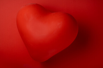 Red balloon in the shape of heart on red background top view flat lay copy space