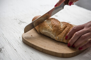 Cutting fresh bread baguette in wood table on white rustic table