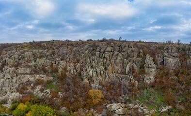 A picturesque stream flows in the Aktovsky Canyon, surrounded by autumn trees and large stone boulders