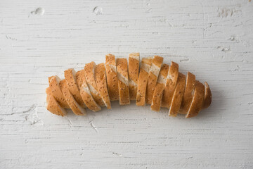 Fresh bread sliced baguette on rustic white table top view
