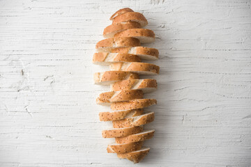 Fresh bread sliced baguette on rustic white table top view