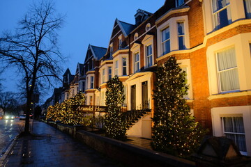 Multiple festive decorated houses in Cambridge city, people putting christmas trees in front of their houses as the holidays approach in december