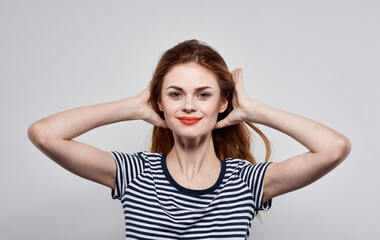 Energetic woman in a striped T-shirt gestures with her hands on a gray background Copy Space