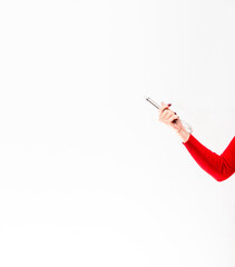 A whisk made of metal for cooking is held by a female hand on a white background.