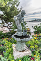 Obraz premium Porteuse d'eau dans un massif de fleurs en pierre en bord de mer 