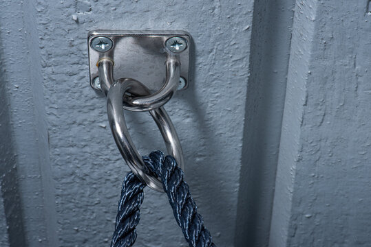 Blue rope going through a stowage bracket ojn a wall..