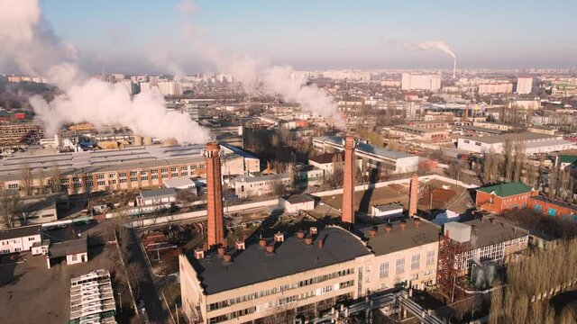 Aerial view smoke clouds from boiler pipes on industrial area. Smoking chimney on plant industrial city