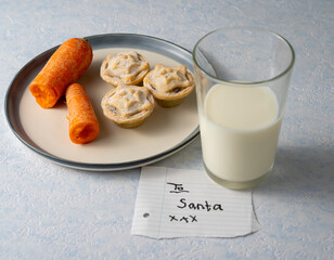 Carrot, yummy mince pies, and a glass of milk with a note "To Santa" © Max Rushent/Wirestock