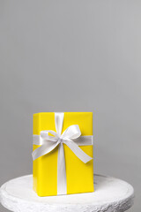 Demonstrating trendy colors 2021 - Gray and Yellow. Yellow gift with white ribbon