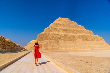 A young tourist in a red dress at the Stepped Pyramid of Djoser, Saqqara. Egypt. The most important...
