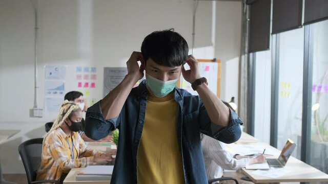 4k slow motion Young Asian man wearing face mask for protective and prevention covid-19 portrait in office. Working after lockdown
