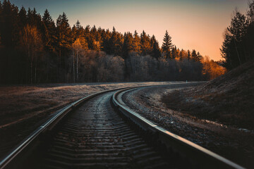 railway tracks in the middle of the forest in autumn at sunset